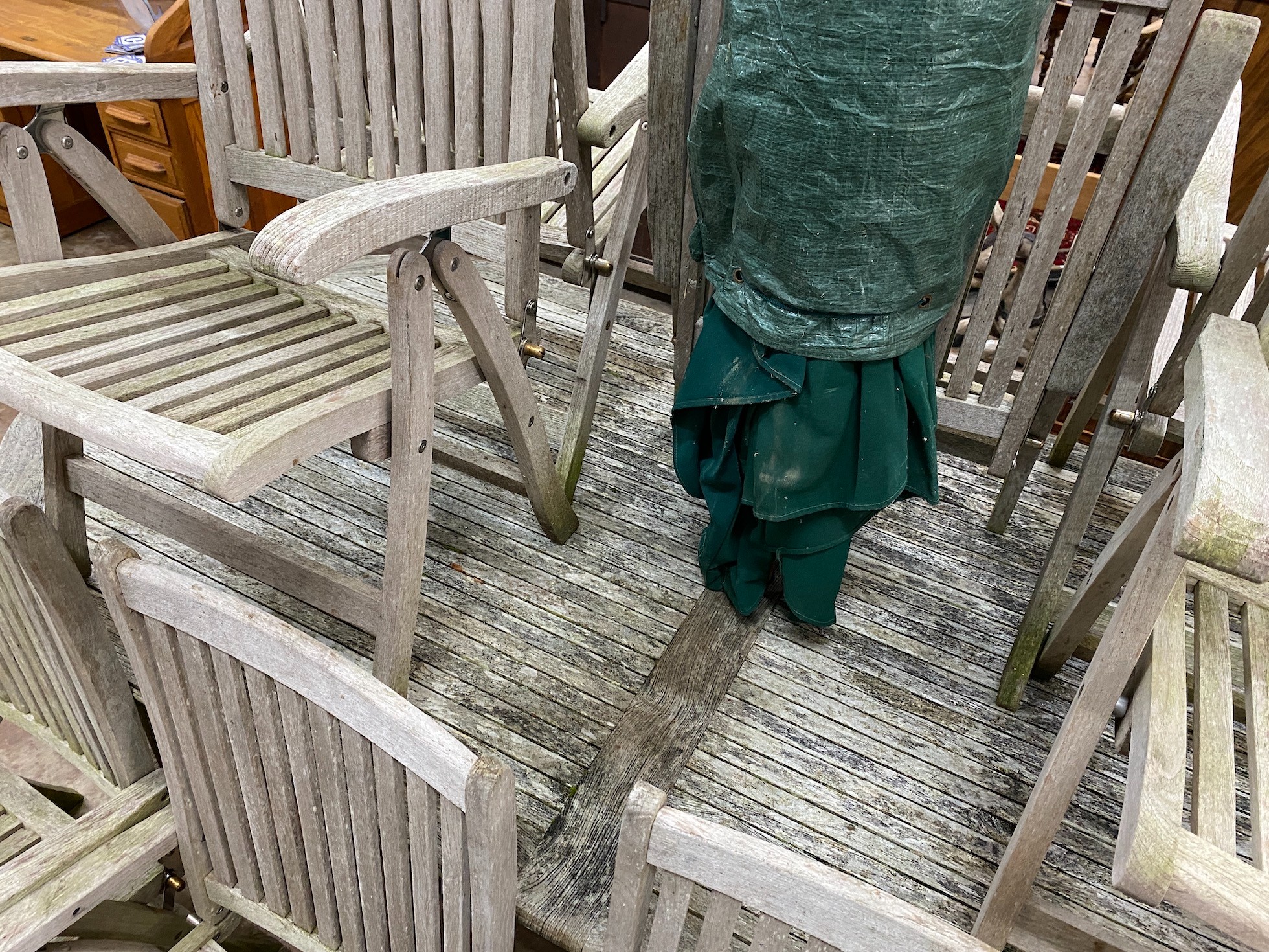 An oval teak garden table, length 260cm, depth 119cm, height 74cm together with eight folding chairs, parasol and cast metal stand.